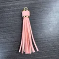 Pink PU leather tassel keychain pendant with a gold metal ring on a dark wood background - Pink