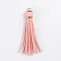 Pink PU leather tassel keychain pendant with a gold metal ring on a dark wood background - Pink