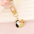 Macro shot of cartoon cat reading under a lamp enamel keychain with gold plating - Cat Reading with Lamp