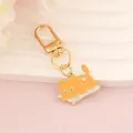 Detail of orange cartoon cat keychain with golden lobster clasp and heart ornament - Cat Lying on Book