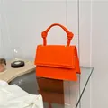Fashionable bright orange crossbody bag with unique knotted handle and flap closure - Orange