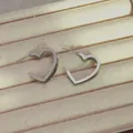 Elegant silver heart-shaped hoop earrings with layered metal lines on beige velvet tray - Silver Double Layer Heart Hoop