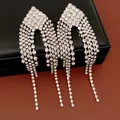 Close-up of elegant rhinestone diamond-shaped fringe earrings displayed on a black jewelry box - Silver