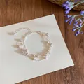 Detaillierte Nahaufnahme eines eleganten mehrlagigen Perlenarmbands auf einem weißen Hintergrund - Rosa/Silber Mehrlagiger Stil