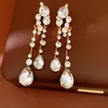 Detailed view of elegant gold-tone earrings with teardrop and round rhinestones - Silver Earring Post Style / Gold-White