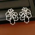 Detailed view of 18k gold plated silver needle hollow flower stud earrings with zircons - Silver