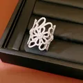 Detailed macro view of an 18K gold plated ring with zircon inlaid hollow flower design - Silver
