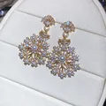 Close-up of vintage snowflake earrings with sparkling zircons and elegant white pearls - Gold