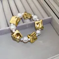 Nahaufnahme eines eleganten Armbands mit goldenen Elementen und glänzenden Perlen - Armband / Gold/Weiß