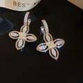 Detailed close-up of 18k gold-plated floral hoop earrings featuring sparkling zircons. - Flower Style / Silver