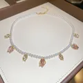 Gros plan d'un collier ras de cou en perles avec des pendentifs tulipes roses élégants - Style Pendentif Tulipe / Blanc-Rose
