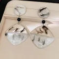 Close-up of resin earrings featuring elegant black and white ink-wash marble patterns - Geometric Dangle Earrings