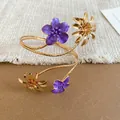 Elegant gold-tone upper arm cuff featuring purple enamel flowers and metal daisies. - Purple