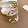 Close-up of pink enamel flower and golden sunflower details on a spiral arm cuff - Pink