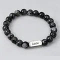 Detailed shot of natural stone beads bracelet with custom engraved metal name tag Aaron - Black Spectrolite