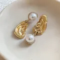 Detailed macro view of gold ear-shaped earrings with faux pearl and crystal accents - Western Statement Ear Shape Style (HE33135) / Gold