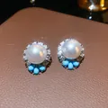 Detailed view of elegant white pearl stud earrings with sparkling rhinestones and blue beads. - Stud Earrings / Silver Needle / Silver Blue