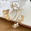 Detailopname van een elegante gouden armmanchet met emaille bloemen en vlinderdetails - Khaki