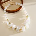 Detailed view of white acrylic geometric beads on a chunky gold-toned necklace - Clear
