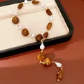 Detail view of irregular brown acrylic and white pearl necklace on jewelry tray - Brown