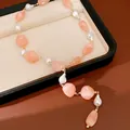 Detail view of irregular peach acrylic beads and baroque pearls on a gold-tone necklace chain - Pink