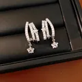 Primo piano di eleganti orecchini a lobo a tre strati con stelle e zirconi luminosi. - Argento