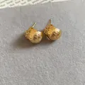 Detailed close-up of elegant gold-plated flower stud earrings with sparkling zircon accents. - Gold
