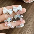 Détail rapproché de boucles d'oreilles nœud blanc avec franges de perles de cristal. - Gland de Nœud / Blanc-Rose-Vert