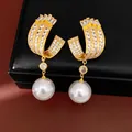 Detailed macro view of U-shaped gold plated earrings with zircons and white pearls - Gold