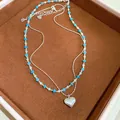 Close-up of elegant heart pendant and blue turquoise beaded necklace in a brown display box - Two-Piece Set / Silver & Blue