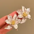 Close-up of French iris metal earrings with elegant pearlescent finish and gold stamen - 3D Iris Flower (Silver Post) / Beige