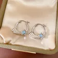 Detailed view of silver-toned hoop earrings featuring a blue zircon shooting star motif - Silver