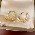 Close-up of gold shooting star hoop earrings with pink zircon in a satin jewelry box - Gold