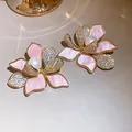 Nahaufnahme eleganter rosa Blumenohrringe mit Perle und Zirkon-Blütenblättern. - Rosa
