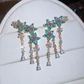 Primo piano di eleganti orecchini a fiore con zirconi blu e rosa per donne raffinate - Stile Nappina a Fiori (HE32946) / Oro