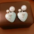 Dettaglio di orecchini a cuore cangianti con fiocco e grandi perle bianche. - Stile Fiocco Cuore Perla / Bianco/Blu
