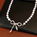 Primo piano di elegante collana di perle con ciondolo a fiocco d'argento - Stile Fiocco Plissettato / Argento (Perla Bianca)