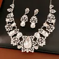 Vue détaillée d'un élégant ensemble de bijoux argentés avec fleurs de cristal et gouttes - Ensemble Collier Et Boucles d'Oreilles / Argent