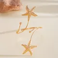 Vue détaillée d'un bracelet de bras doré avec des breloques en forme d'étoile de mer. - Or
