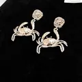 Close-up of silver-toned crab-shaped stud earrings with ornate hammered metal detail - Silver