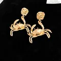 Detailed view of gold-colored crab stud earrings with textured finish and nautical style. - Gold