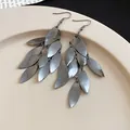 Close-up of gunmetal grey metal leaf tassel earrings with brushed texture on cream plate. - Style 3 Hook Gun Black
