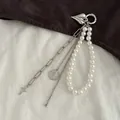 Nahaufnahme eines silbernen Herzanhängers und einer Perlenkette für Taschen - Mehrlagiges Perlenkreuz (0070)