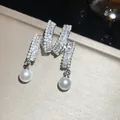 Close-up view of elegant zircon and pearl drop earrings with a luxury sparkling finish - Stud Earrings / Silver