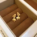Detailed close-up of golden goldfish stud earrings with matte texture in a brown velvet box - Steel Pin Koi Fish Style (37#)