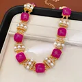 Primer plano de un collar vintage con piedras magenta y perlas en un estuche de joyas - Collar / Dorado-Púrpura
