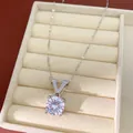 Detailed macro view of a silver V-shaped pendant necklace with round zircon in a jewelry box. - Silver White