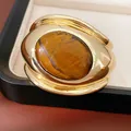 Close-up of a bold gold-toned cuff bracelet featuring a large oval tiger's eye stone - Tiger Eye Stone (HB5741) / Gold