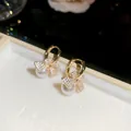 Macro view of French vintage gold bow earrings with zircon stones and elegant white pearls - Ear Buckle / Gold-White