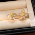 Detailed close-up of gold-plated four-leaf clover ear clips set with cubic zirconia stones - Ear Clip (HE32738) / Gold